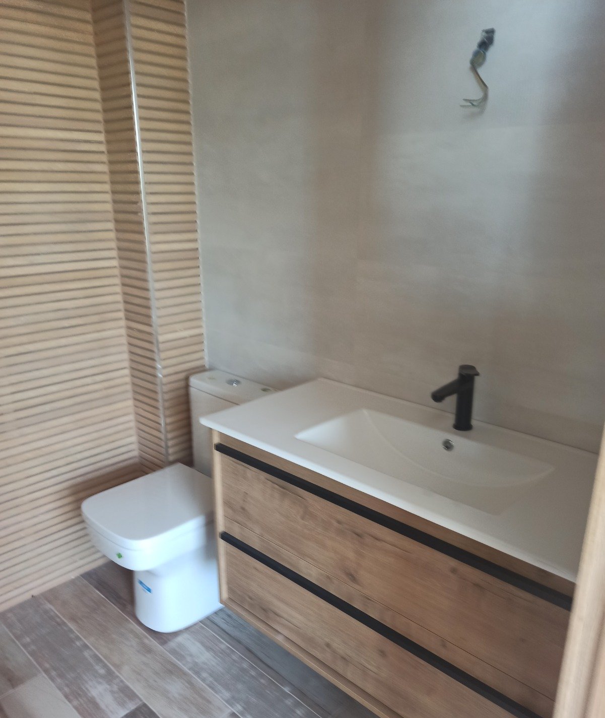Baño reformado por Reformas CC García: mueble de madera y grifería negra mate