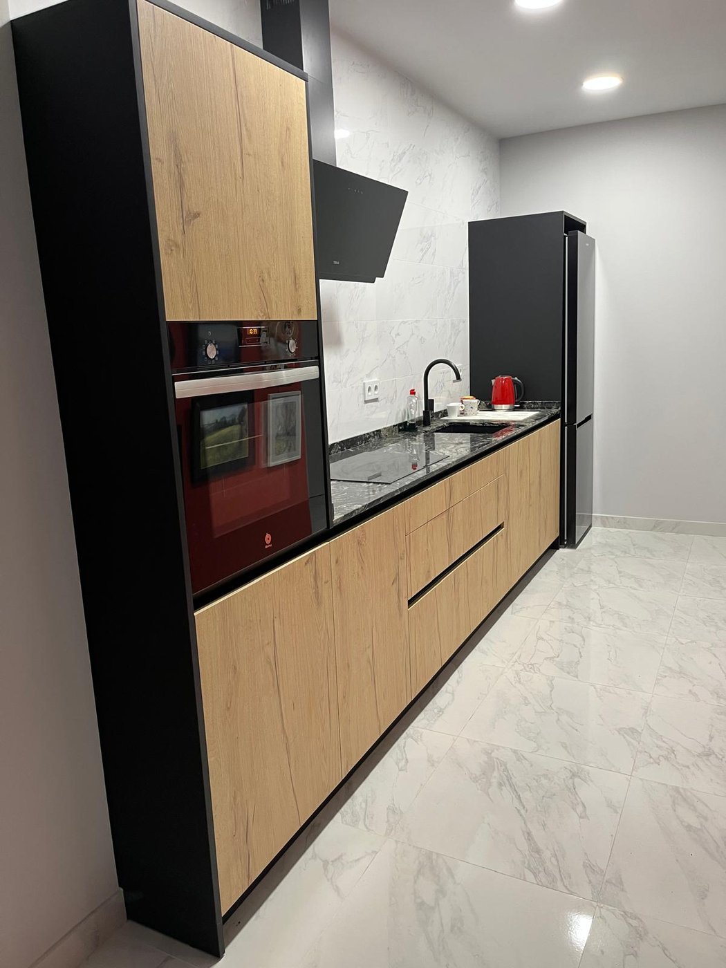 Cocina reformada por Reformas CC García en negro y madera, con horno integrado